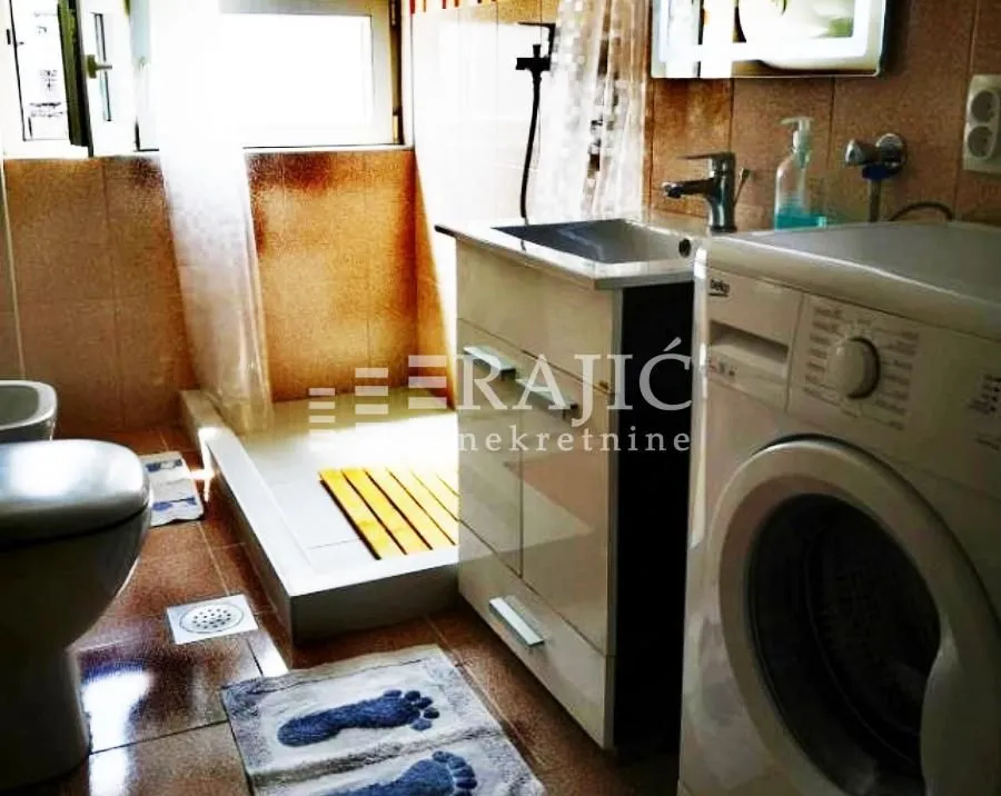 Small bathroom with a shower cabin, sink, and washing machine.