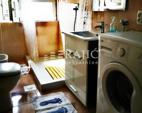 Small bathroom with a shower cabin, sink, and washing machine. - image 14