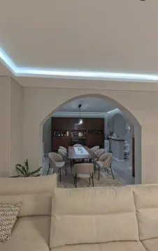 Living room overlooking the dining area and kitchen through an archway. - image 2