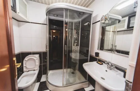 Bathroom equipped with a shower cabin, washbasin, and toilet. - image 14