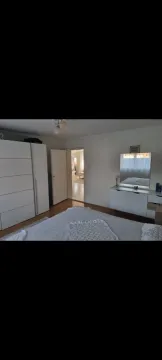 A simply furnished bedroom featuring a white wardrobe and dresser. - image 10