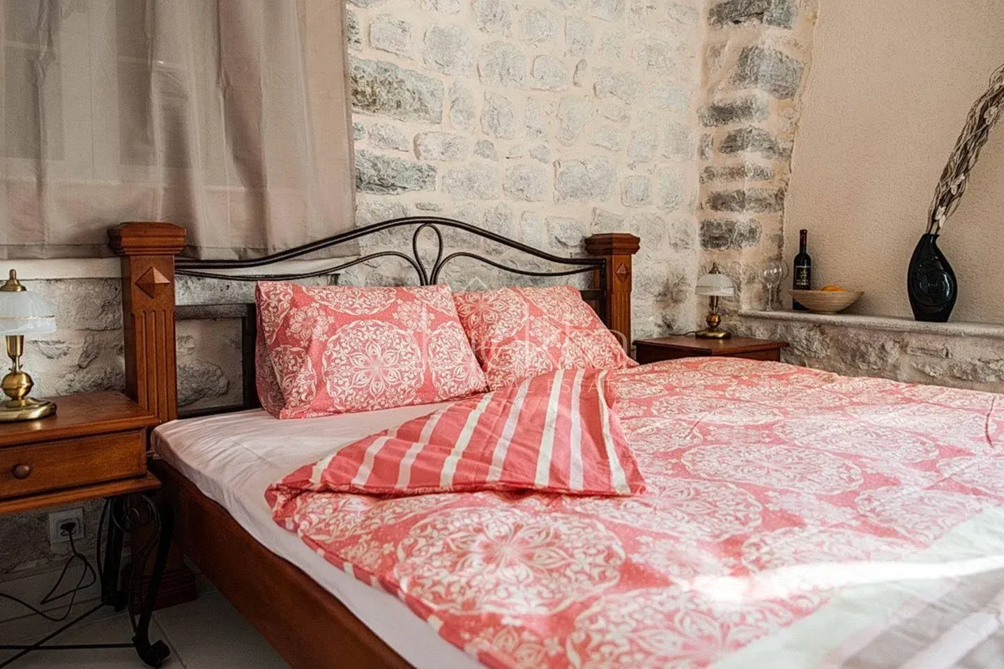 Bedroom with a double bed and a stone wall.