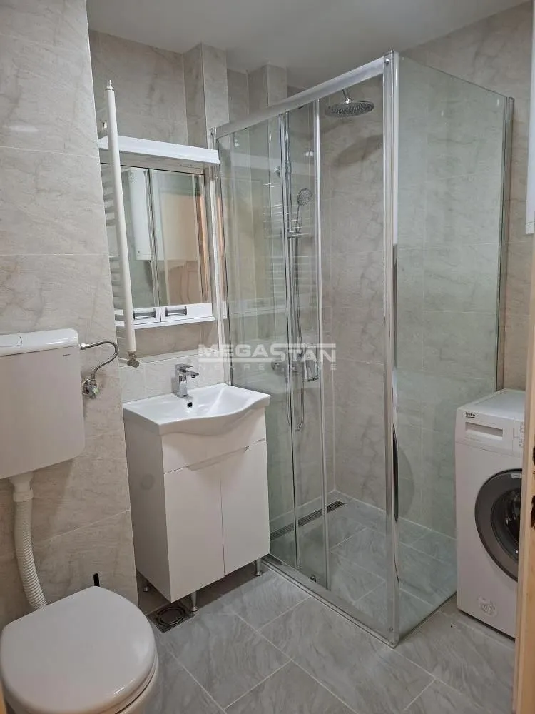 Bathroom equipped with a shower cabin, washbasin, and washing machine.