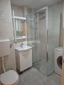 Bathroom equipped with a shower cabin, washbasin, and washing machine. - image 6