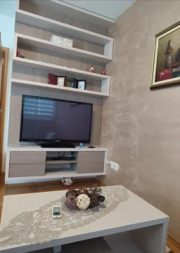 Dnevna soba sa zidnim policama, televizorom i klub stolom. - image 10