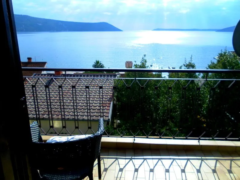 Pogled na more sa terase sa metalnom ogradom i stolicom.