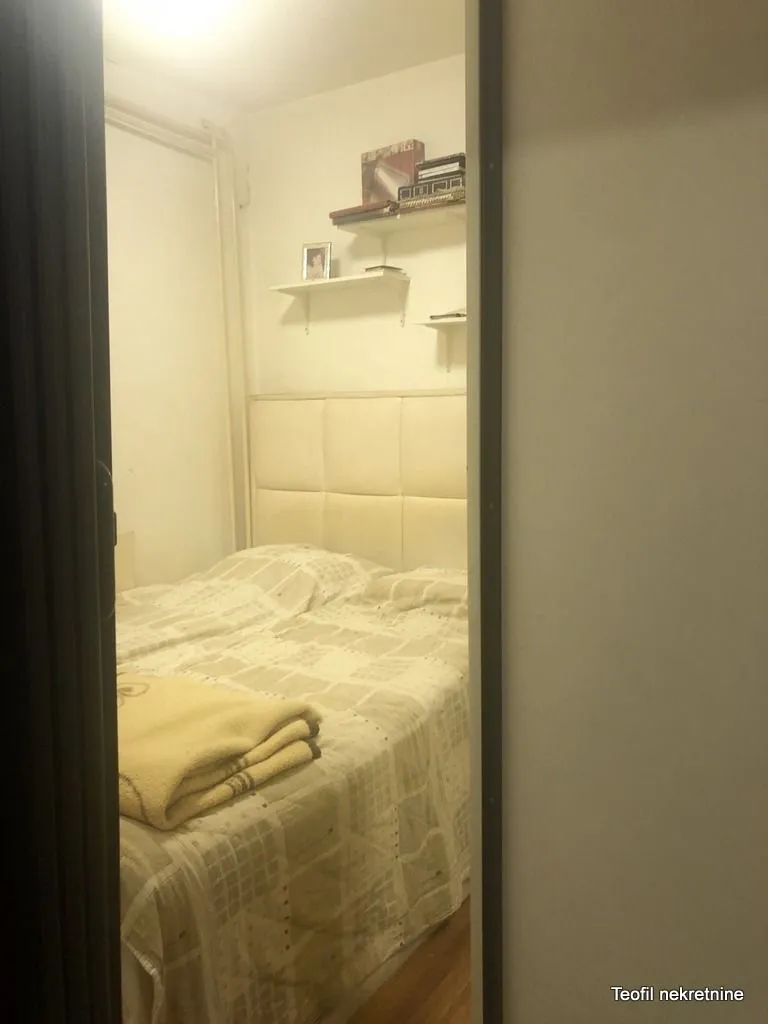Pogled iz hodnika na nameštenu spavaću sobu sa bračnim krevetom.