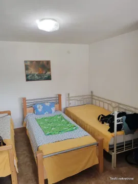 Spavaća soba sa tri kreveta i slikom na zidu. - image 7