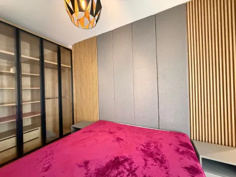 Moderna spavaća soba sa bračnim krevetom, tapaciranim uzglavljem, drvenim panelima i ugradnim ormarom sa staklenim vratima. - image 7