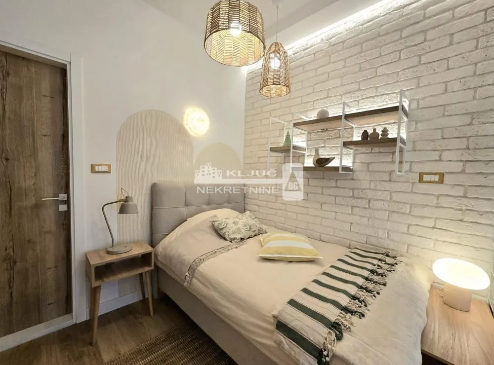 Small bedroom with a bed, decorative wall, and shelves.