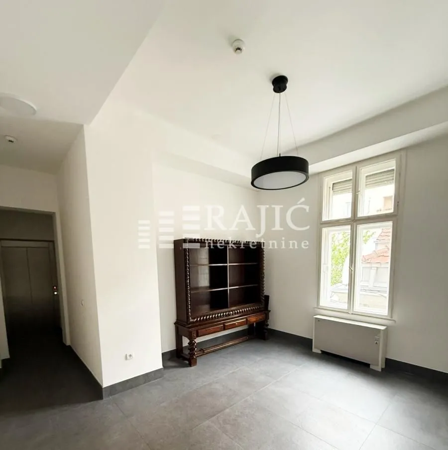 Empty room with dark floor tiles and a wooden dresser.
