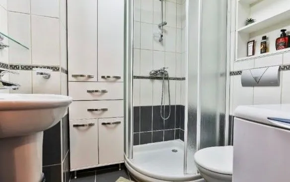 Kupatilo sa tuš kabinom, umivaonikom i ormarićem za odlaganje.