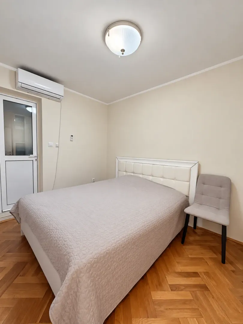 Spavaća soba sa bračnim krevetom, klima uređajem i izlazom na terasu.