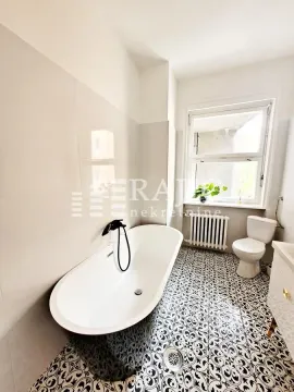Bright bathroom with a freestanding bathtub, toilet, and window. - image 16