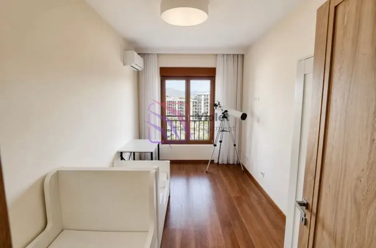 Small bedroom with a bed, desk, and telescope by the window.