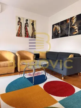 Dnevni boravak opremljen garniturom, stočićem i dekorativnim slikama na zidu. - image 4