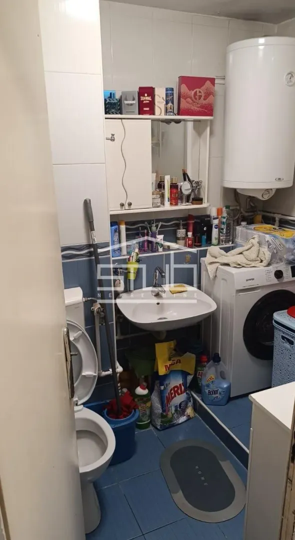 Small bathroom with a sink, toilet, washing machine, and water heater.