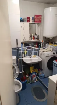 Small bathroom with a sink, toilet, washing machine, and water heater. - image 3