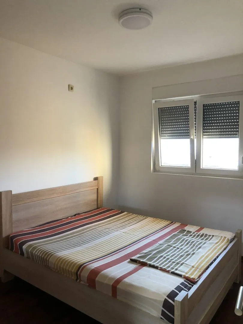 A simply furnished bedroom with a double bed and a window.