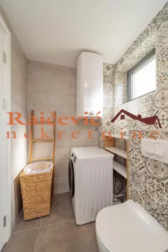 Bathroom equipped with sanitary ware, washing machine, and decorative tiles. - image 3
