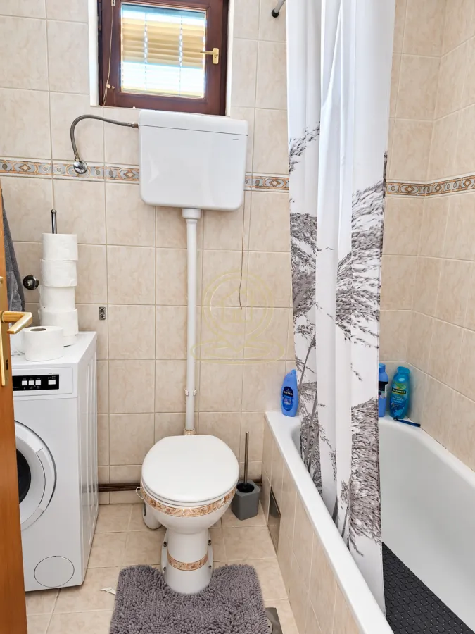 Small bathroom with a bathtub, toilet, and washing machine.