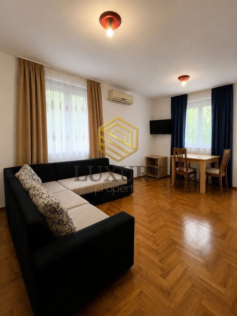 Living room with a sofa set, dining table and parquet flooring.