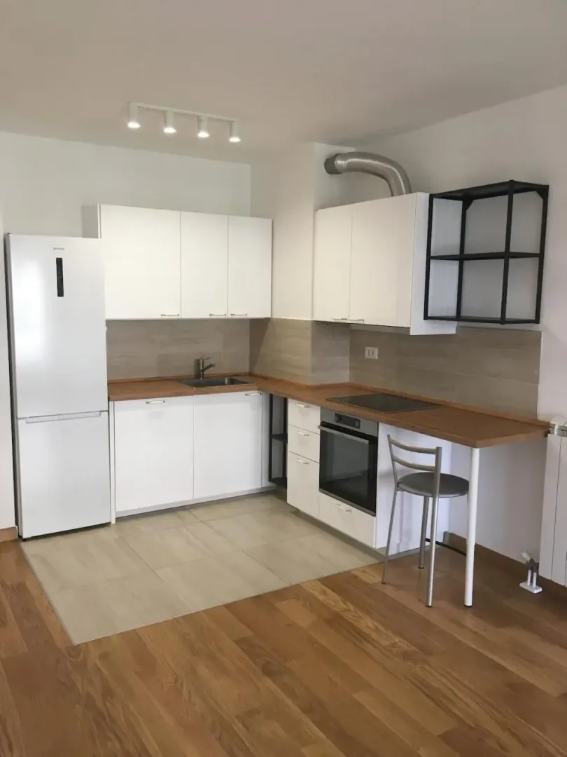 Kitchen equipped with white cabinets, built-in appliances, and a refrigerator.