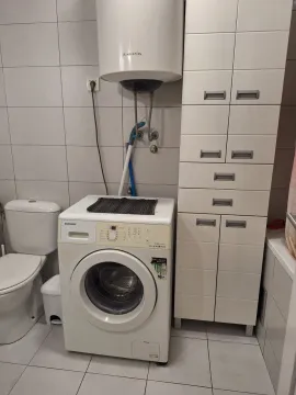Kupatilo opremljeno toaletom, mašinom za veš, bojlerom i bijelim ormarićem. - image 7