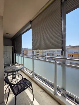 Furnished balcony with a table and chairs and a view of the surrounding buildings. - image 2