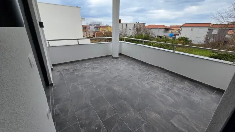 Prostrana nenamještena terasa sa pločicama i pogledom na naselje. - image 4