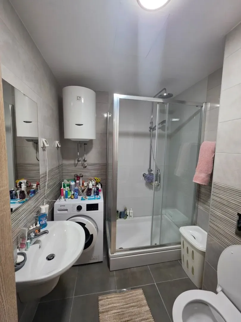 Bathroom with a shower cabin, washbasin, and washing machine.