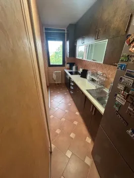 Uska kuhinja sa tamnim elementima i pločicama na podu. - image 5