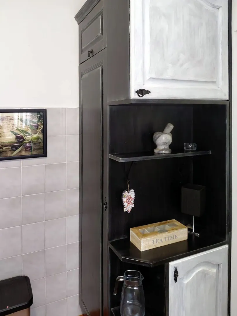 Crno-bijeli kuhinjski element sa policama i ukrasnim detaljima.