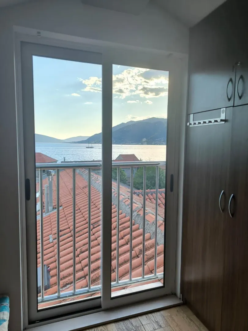 Pogled na more i planine kroz balkonska vrata iz sobe sa plakarom.
