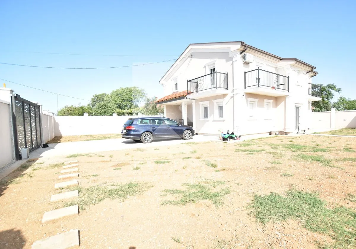 View of the yard and exterior of the house with a parked car.