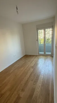 Empty room with wooden flooring and balcony doors. - image 2