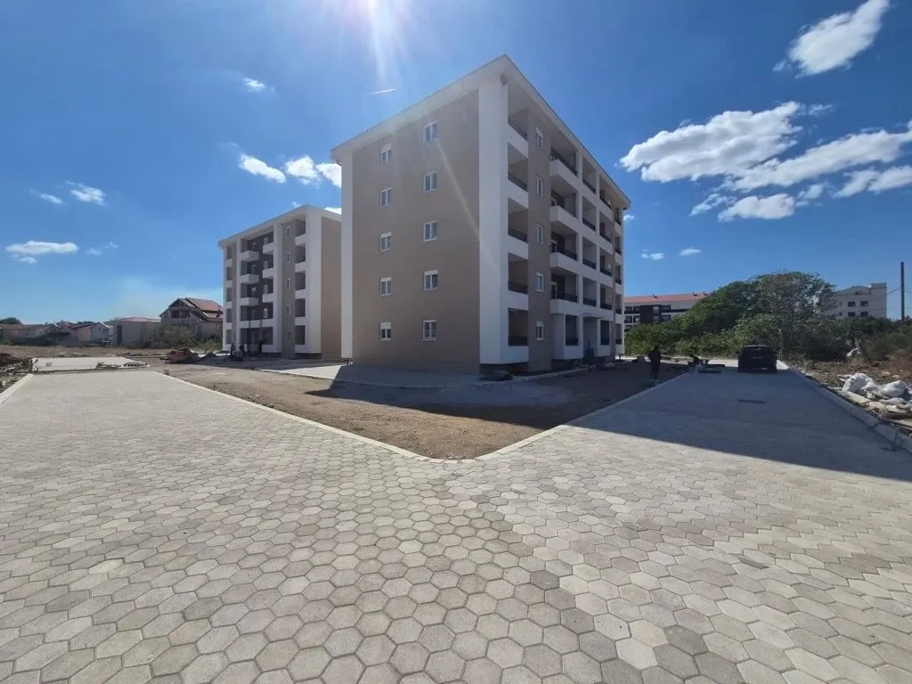 Eksterijer stambene zgrade sa popločanim dvorištem.