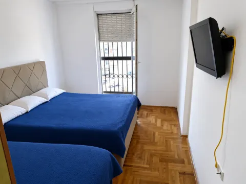 Spavaća soba sa dva kreveta i televizorom na zidu. - image 6