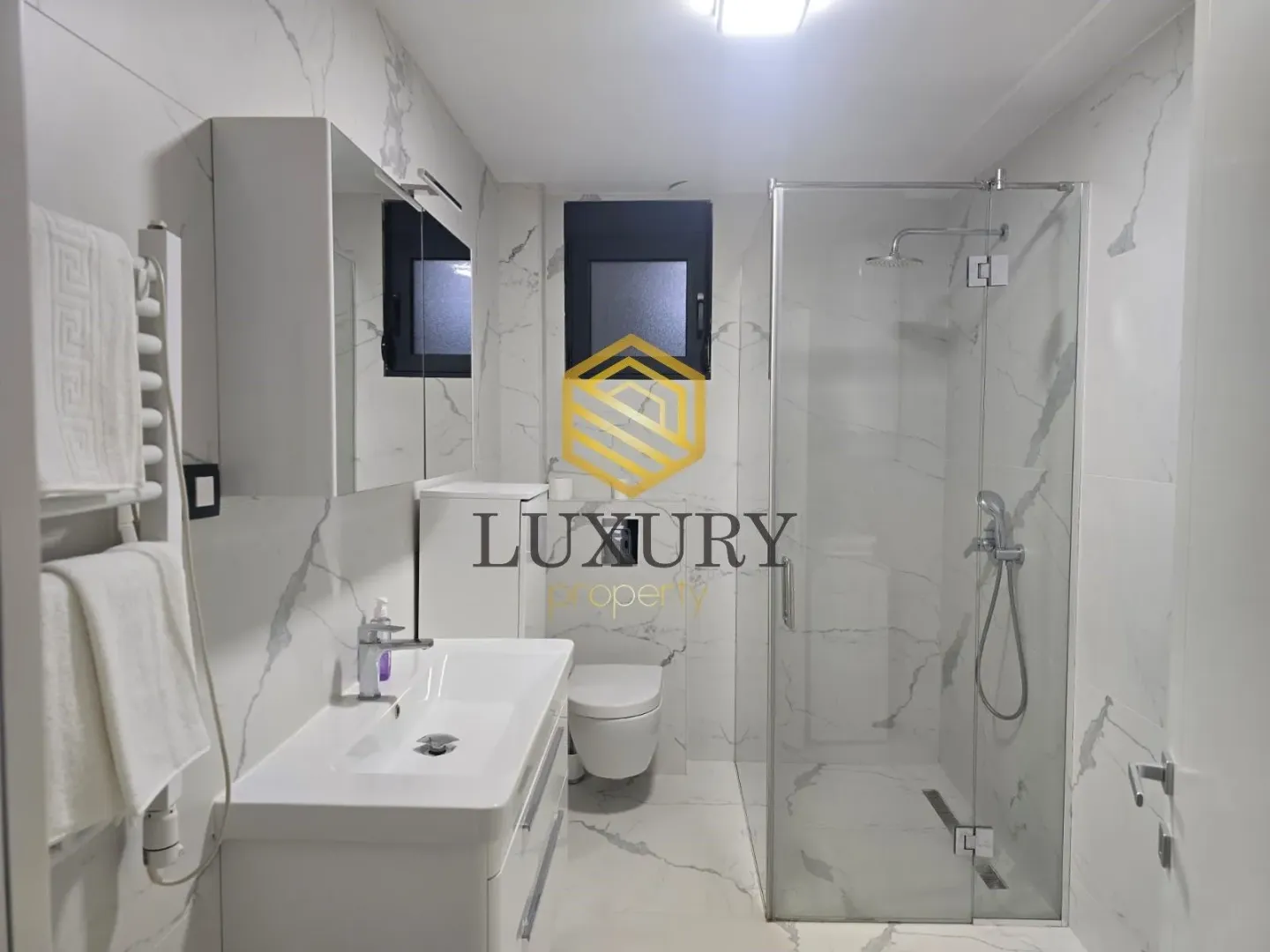 Modern bathroom with a walk-in shower and marble tiles.