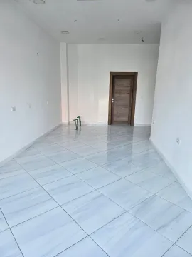 Empty room with white walls, tiled flooring, and a wooden door. - image 4