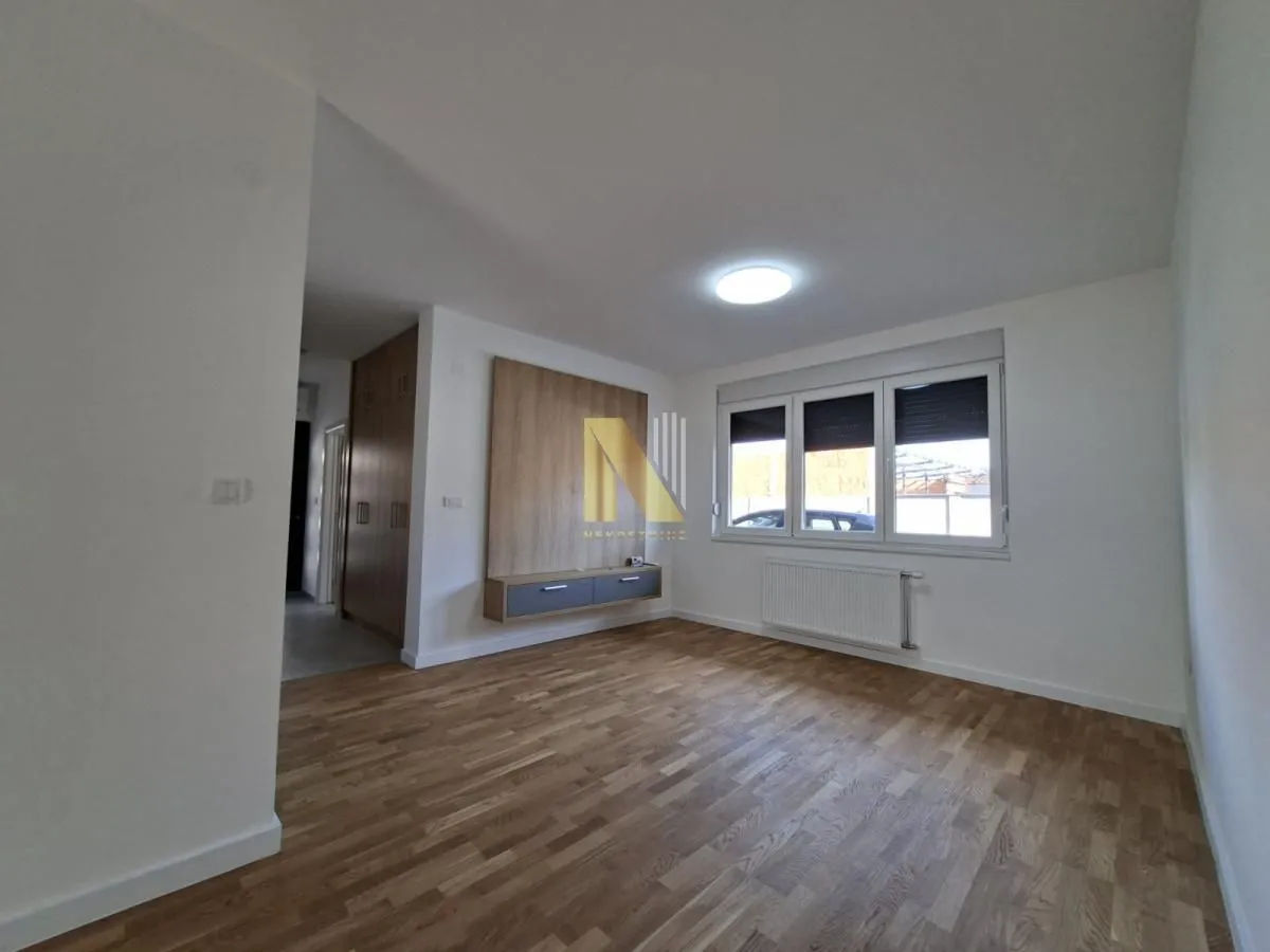 Empty living room with parquet flooring and a wall-mounted TV unit.