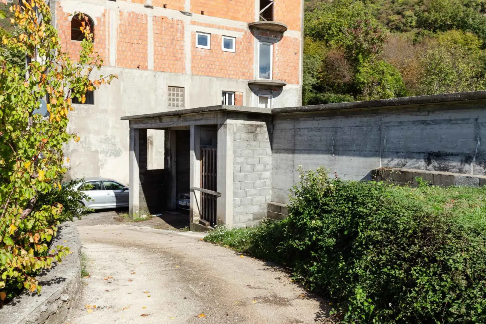Pogled na spoljašnjost zgrade sa pomoćnim objektom i prilazom.