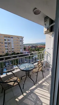 Namtješten balkon sa stolom i dvije stolice i pogledom na grad. - image 5