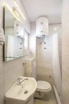 Small bathroom with a sink, toilet, and shower enclosure. - image 6