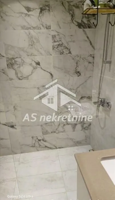 View of a modernly decorated bathroom with marble tiles and a shower cabin.