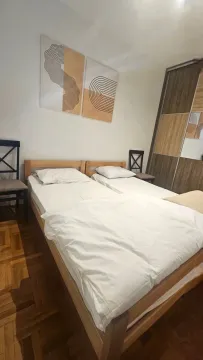 Spavaća soba sa bračnim krevetom, plakarom i ukrasnim slikama na zidu. - image 12