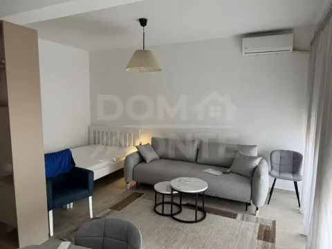 Svijetli dnevni boravak sa garniturom, stočićima i krevetom u pozadini. - image 2