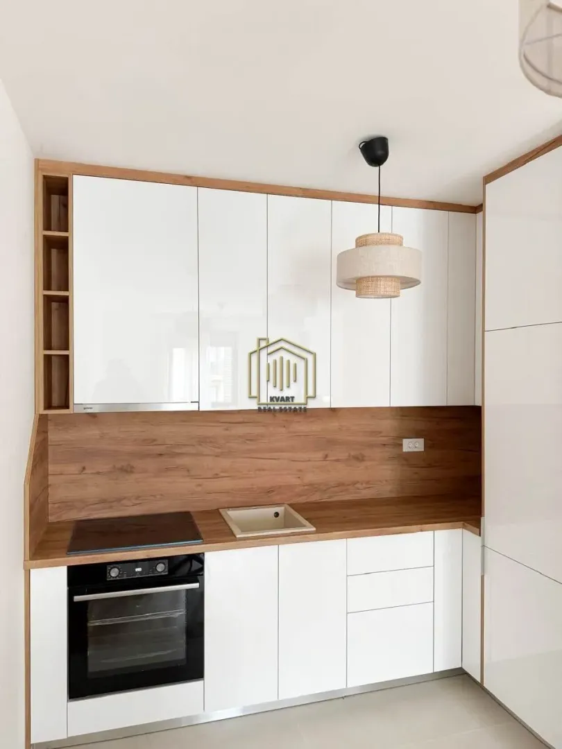 Modern kitchen with white units and wooden details.