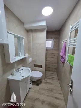 Small tiled bathroom equipped with a vanity sink, toilet, and shower area. - image 18