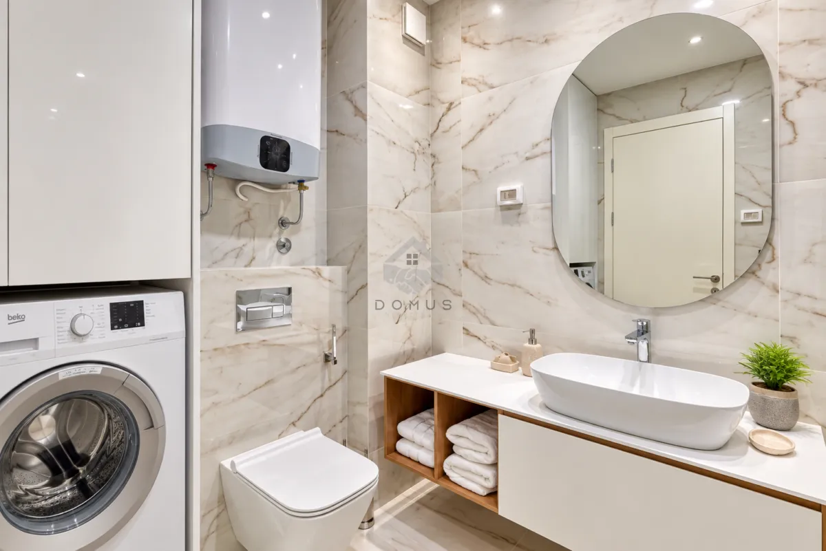 Modernly equipped bathroom with a washbasin, toilet, washing machine, and built-in water heater.
